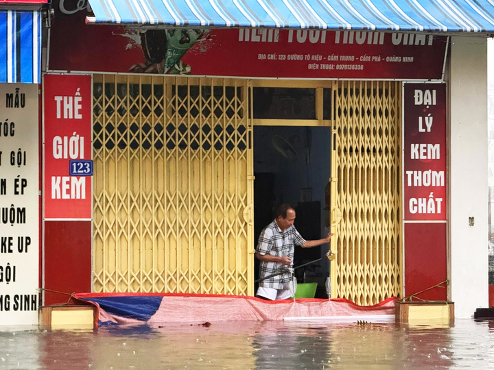 Người dân trên tuyến phố Tô Hiệu, phường Cửa Ông sử dụng bạt chặn trước cửa để hạn chế nước tràn vào nhà.